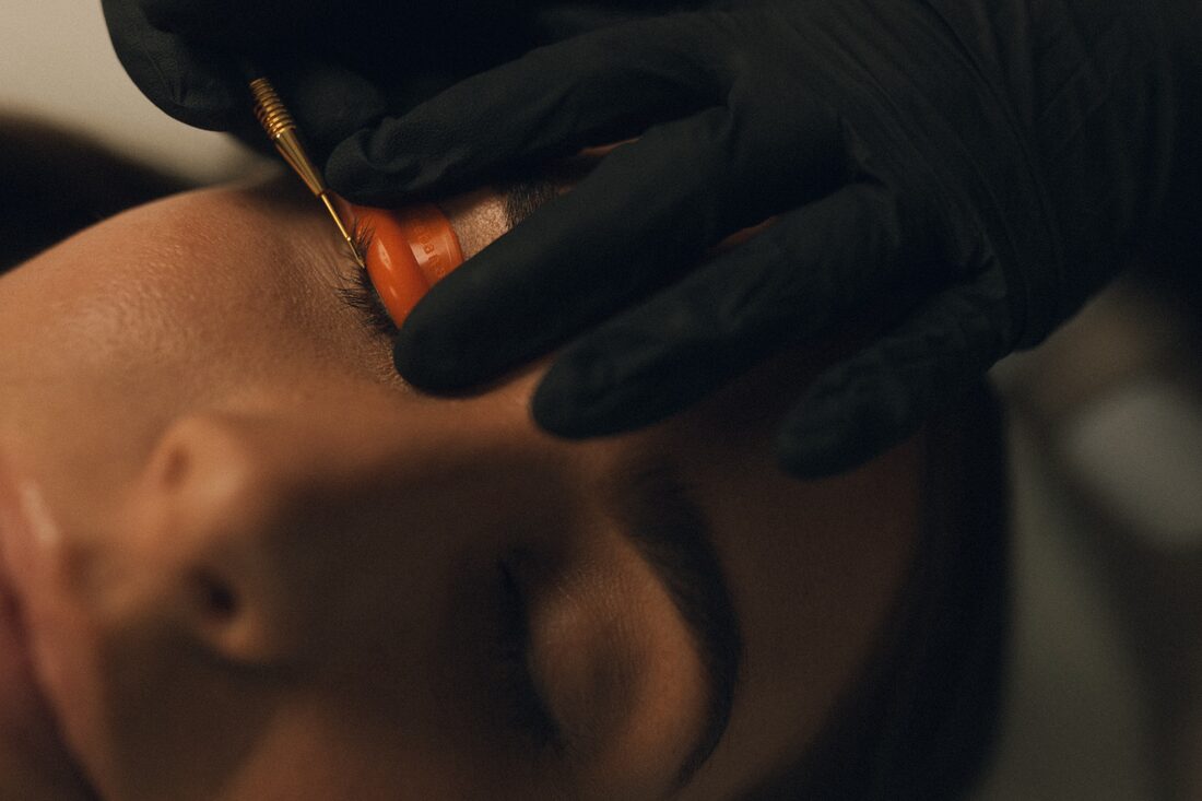Close-up of a lash lift rod being carefully applied to natural lashes